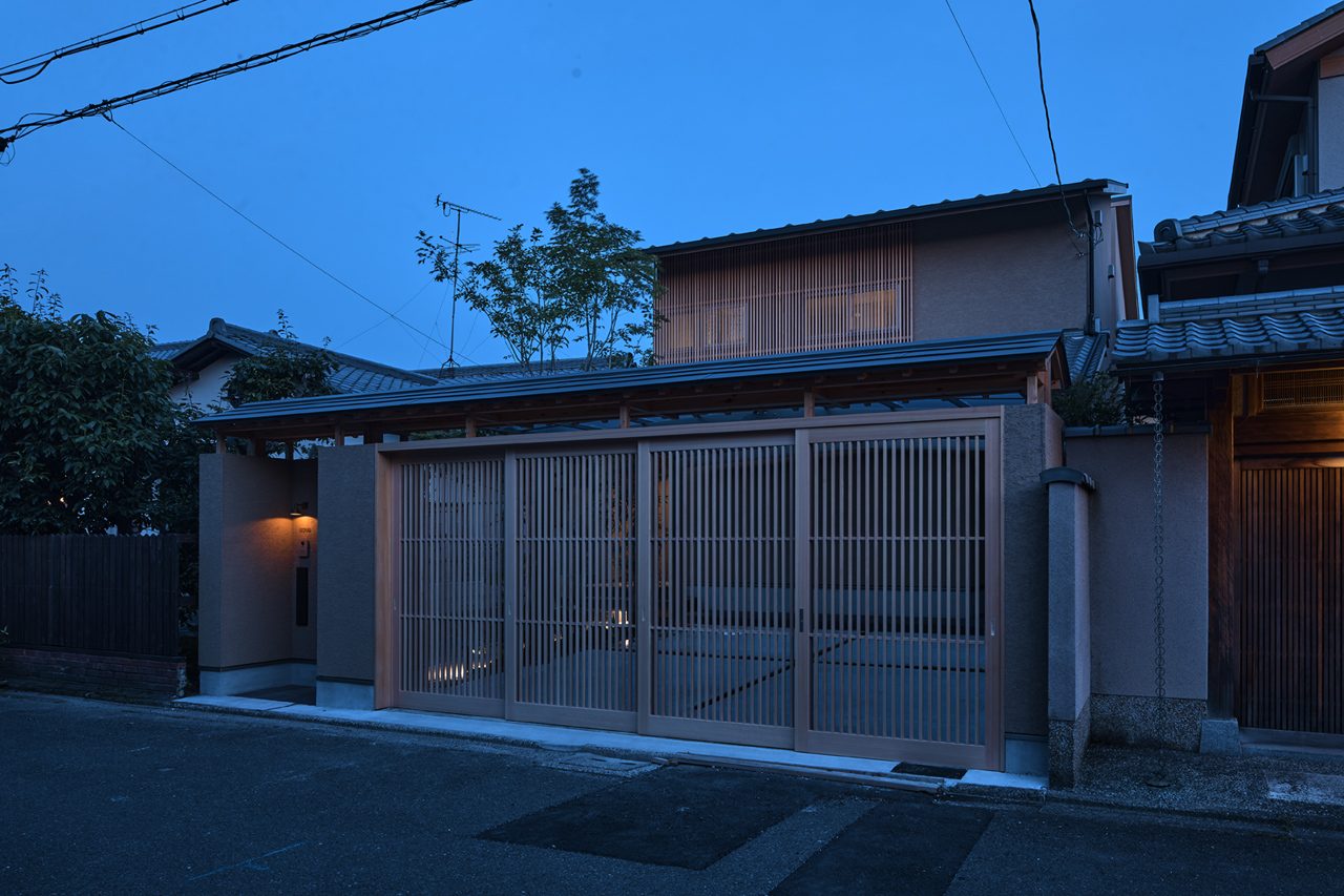 夕暮れの京都の住宅。木の格子戸に灯りがともる外観