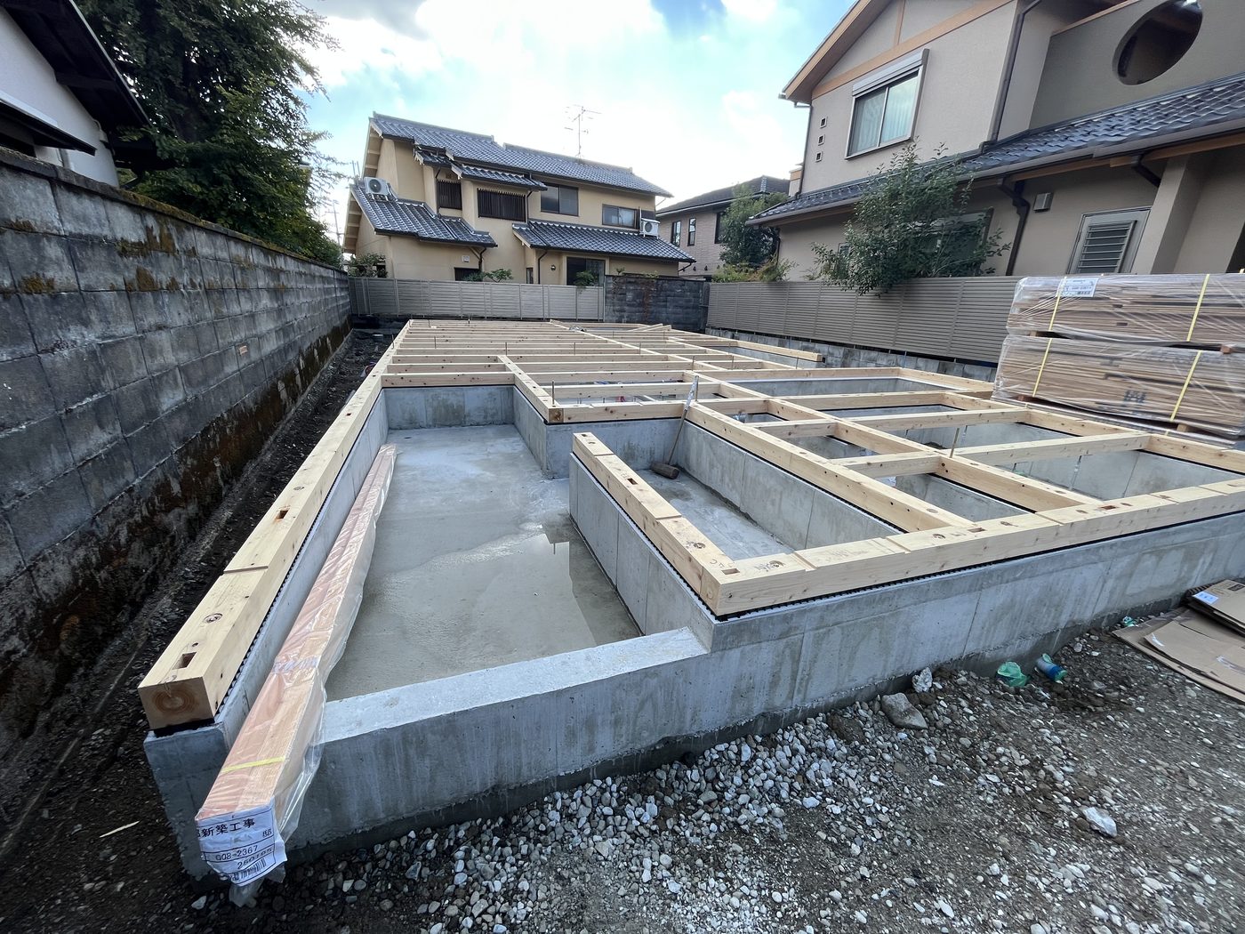 基礎の上に土台が組まれ、材料が整えて置かれた現場
